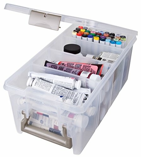 Clear plastic storage box with art supplies including paint tubes and markers