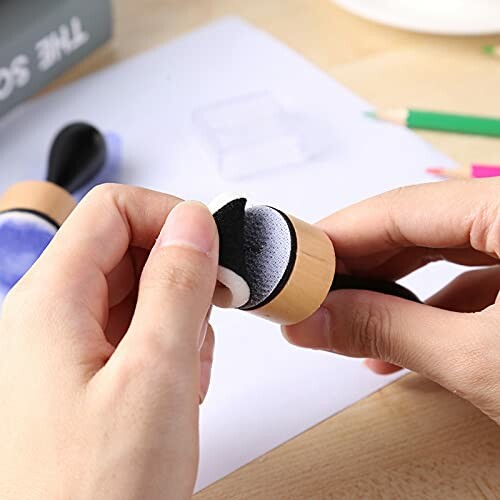 Hands holding a craft tool with a Velcro surface.