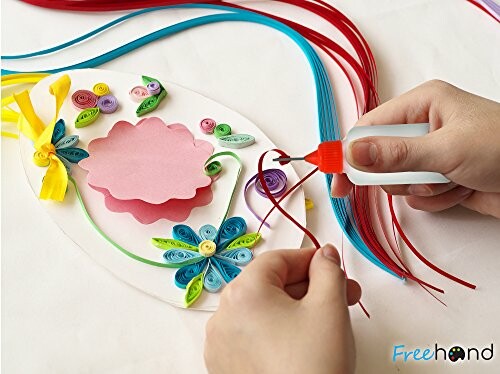 Hands creating a paper quilling craft with colorful strips and glue.